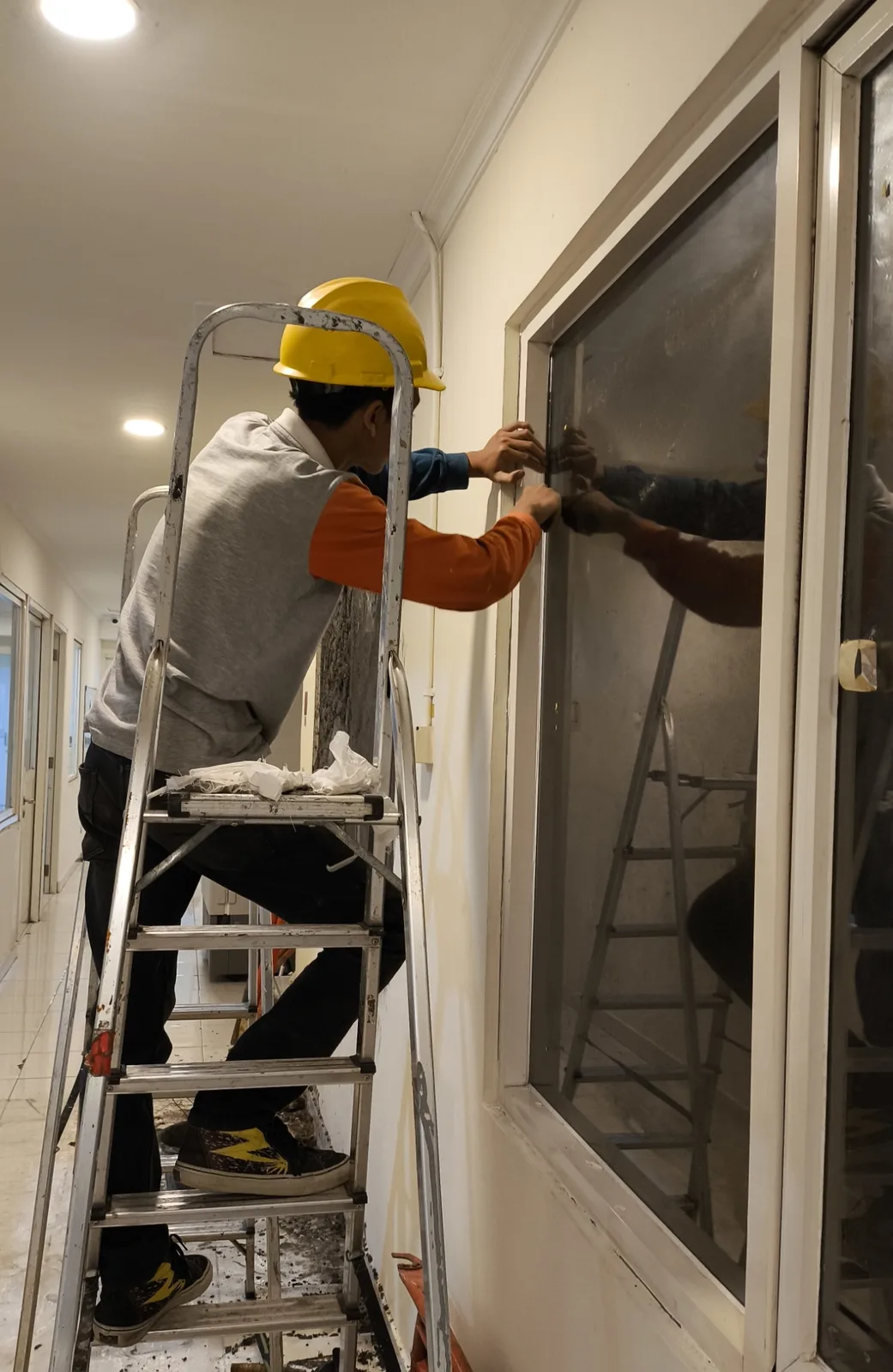 memasang atau merapikan list bingkai kaca pada jendela koridor ruangan dalam ruangan (indoor).